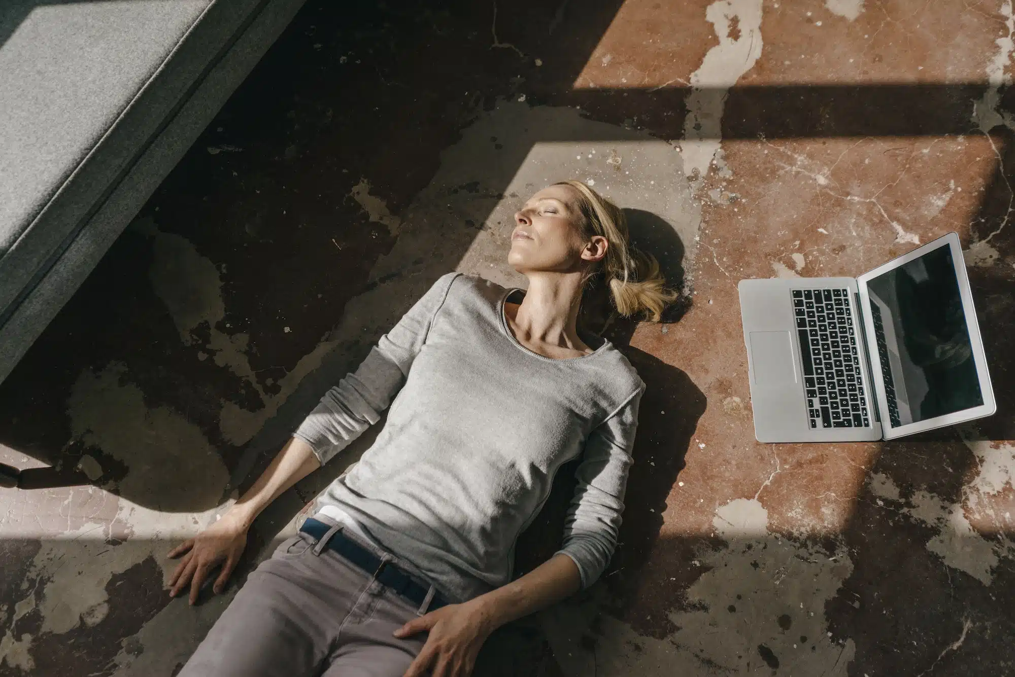 Woman sleeping on the floor next to laptop