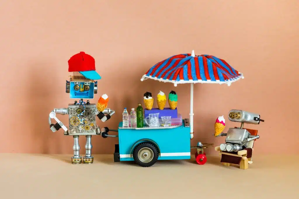 Mobile ice cream lemonade shop. Toy cart with a big umbrella, robot shopman holds waffle cone of ice