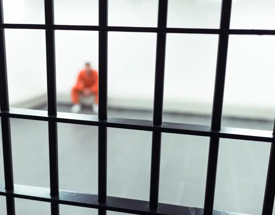 prisoner sitting on bench with prison bars on foreground