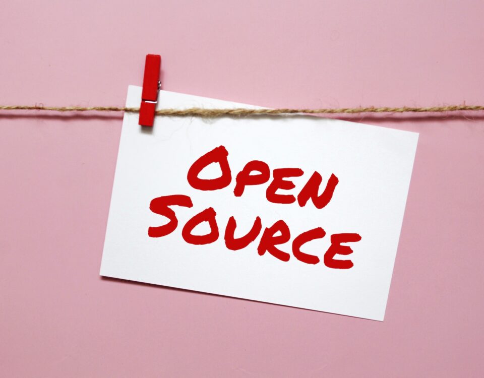 Sticker with the inscription open source hanging on a rope on a pink background