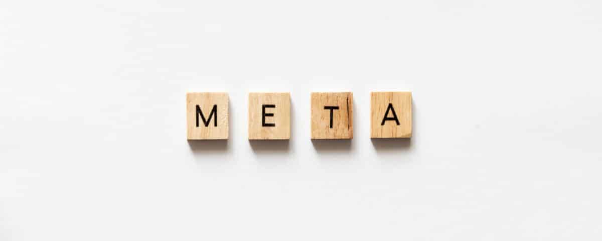 META spelled out with wooden letter tiles on white surface.