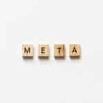 META spelled out with wooden letter tiles on white surface.