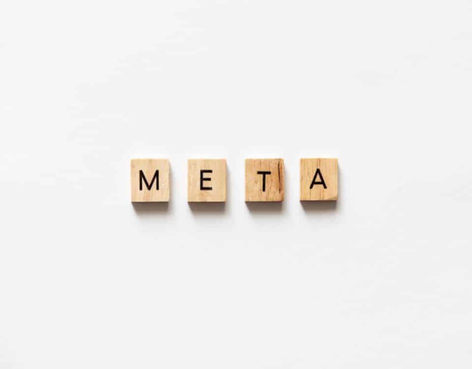 META spelled out with wooden letter tiles on white surface.
