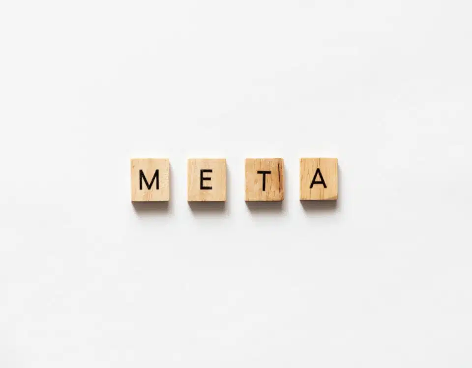 META spelled out with wooden letter tiles on white surface.